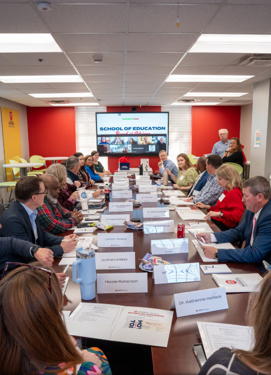 Board of Advisors gather at large table for fall 2024 meeting