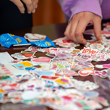 hands reach for colorful stickers, which read love and other positive words