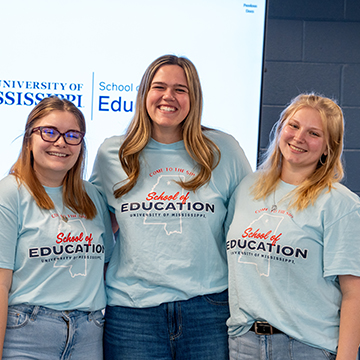 Three female students wear school of education ambassador t shirts 